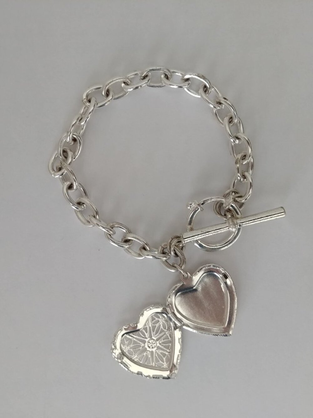 Silver tone chain bracelet with functional intricate heart locket